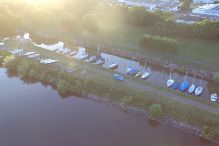 Hafen Boote sind an einem ruhigen Uferparkplatz am Wasser festgemacht, umgeben von Bäumen.